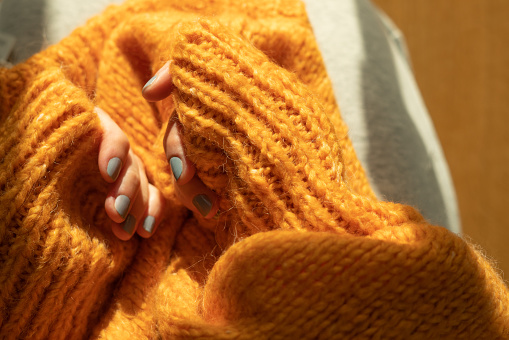 Female hands in orange knitted  sweater