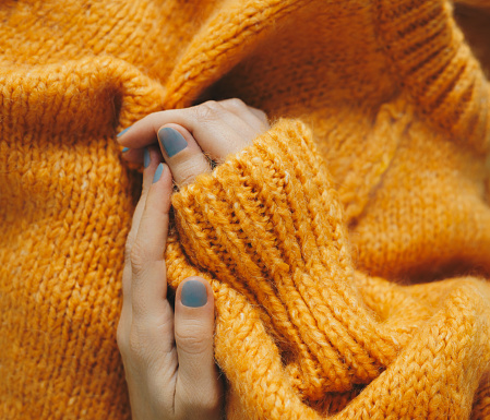 Female hands in orange knitted  sweater