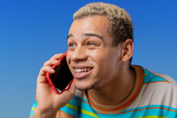 istock Smiling positive man talking by phone, nice joke, smiling. Young guy on blue background. Having smartphone call. 1456886645