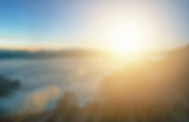 Natural background blurring warm colors and bright sun light. Bokeh or Christmas background Green Energy at sky sunny color orange light patterns plain abstract flare evening clouds blur.