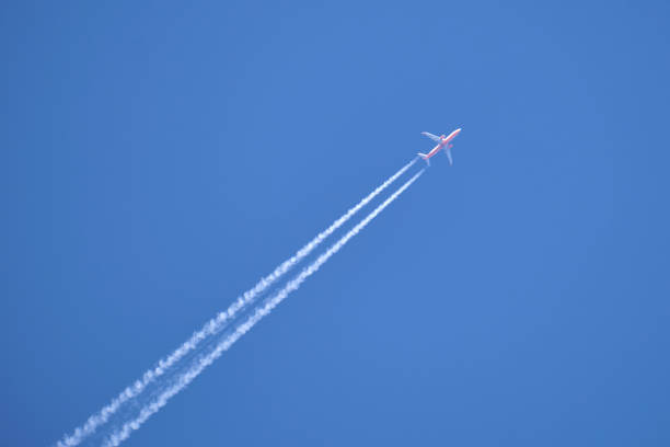 avião distante do jato de passageiros voando em alta altitude em céu azul claro deixando traços de fumaça branca de contrail para trás. conceito de transporte aéreo - flying jet fighter plane air vehicle - fotografias e filmes do acervo