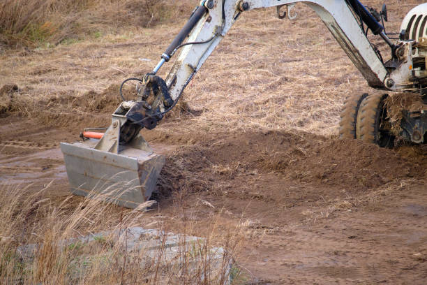 Earth moving tractor preparing place for future house foundation construction. Leveling soil for building new home.