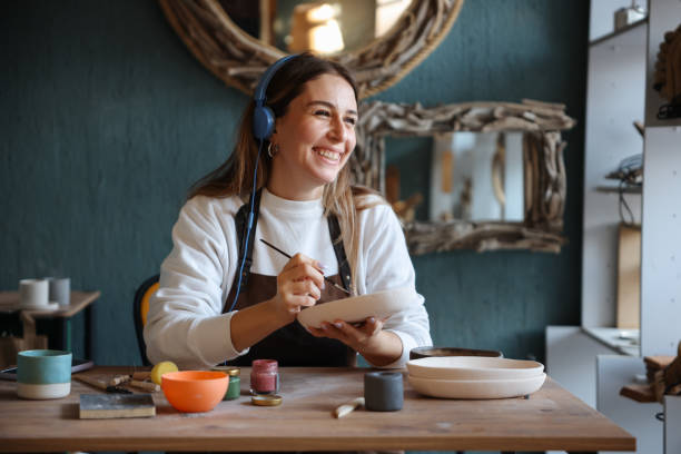 istock Skillful young woman in apron painting pottery at workshop 1456888036