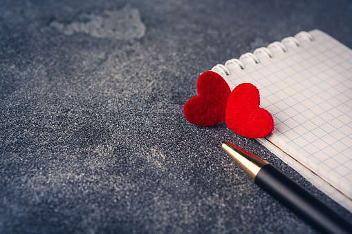 Notepad with pen and red hearts on Valentine's day close-up recording