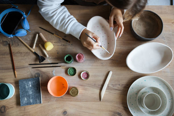 istock Skillful young woman in apron painting pottery at workshop 1456888263