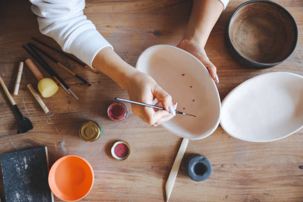 istock Skillful young woman in apron painting pottery at workshop 1456888347