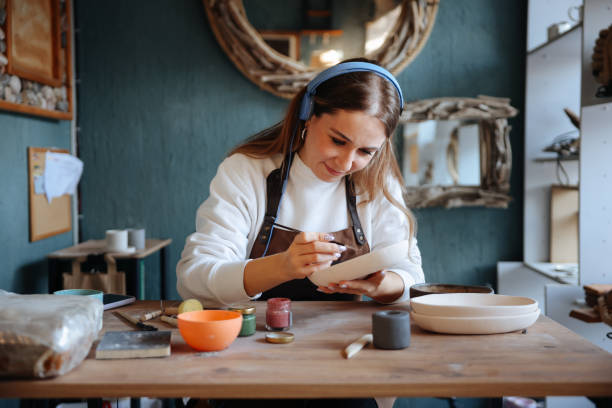 istock Skillful young woman in apron painting pottery at workshop 1456888492
