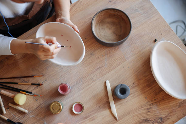 istock Skillful young woman in apron painting pottery at workshop 1456888538