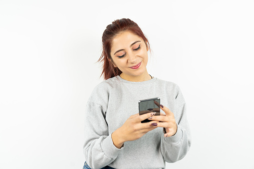 A student in casual clothes prints an online message and does online shopping using a mobile phone and wireless technology on a white background.