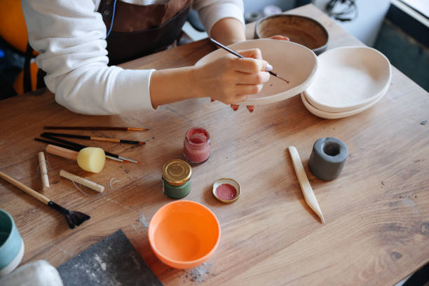 istock Skillful young woman in apron painting pottery at workshop 1456888927