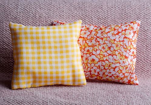 Couple of cushions with checked  and floral pattern on pastel sofa