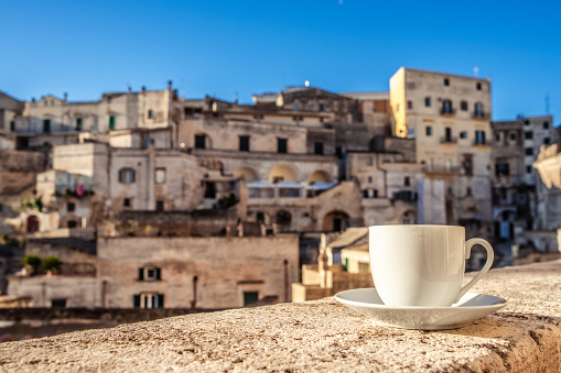 Spectacular morning view with cup of coffee on the balcony in Matera ancient city in Italy. Hillside complex of cave dwellings dating back thousands of years.