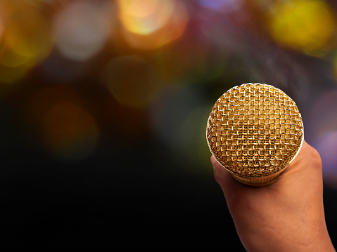 Man holding a golden microphone with beautiful bokeh background