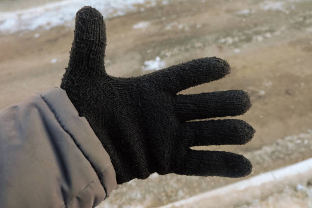 istock Workers hand in a black warm winter woolen glove. Open hand with fingers. Close-up. 1456898253