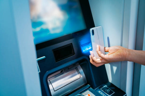 istock Woman scanning her smartphone on the atm 1456898694