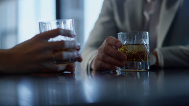 istock Partners hands drinking whiskey in restaurant closeup. Colleagues with bourbon 1456903588
