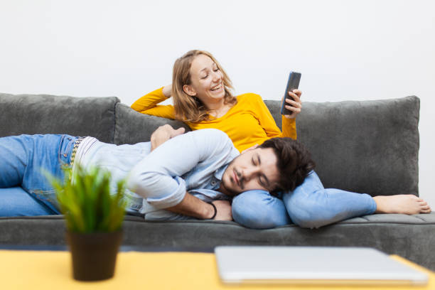 istock boy having a nap on girlfriend's lap while she is looking at smart phone and smiling. 1456904731