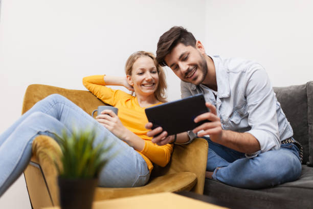 istock couple at home sitting on a sofa looking at tablet computer. both smiling 1456904738