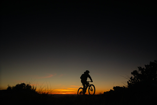 a man makes his way through the abstract nature sky and landscape as the sun sets, bringing ideals of well being, physical fitness, exploration, and adventure to mind.