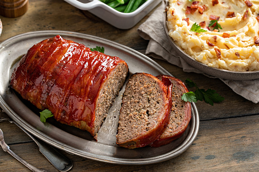 Bacon wrapped meatloaf sliced on a serving plate for dinner
