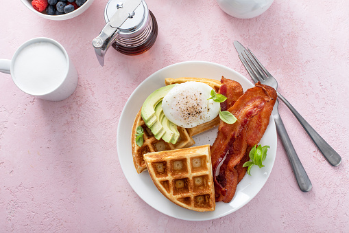 Healthy waffle breakfast plate with bacon, avocado and poached egg