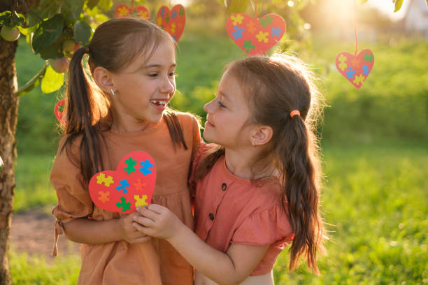 istock Cute loving sisters hold heart with puzzles supporting each other on autism Day 1456907574