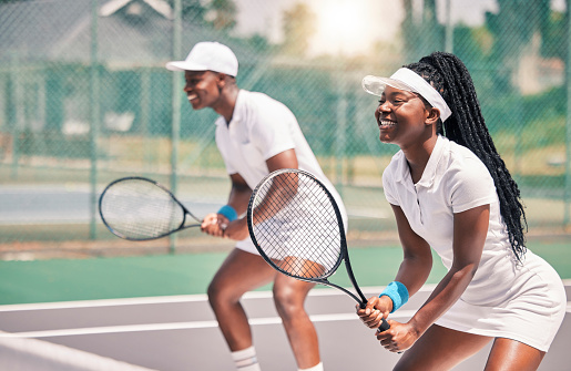 Tennis, sports and competition with a black woman and doubles partner playing a game on a court outdoor together. Fitness, team and exercise with a man and female tennis player at a venue for sport
