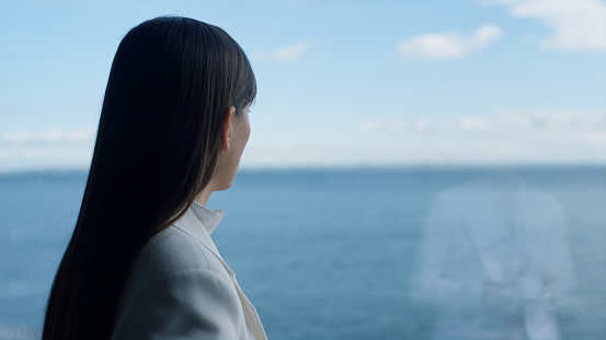 Closeup melancholic woman looking panoramic window. Serious businesswoman enjoying ocean view portrait. Thoughtful entrepreneur thinking at luxury hotel overlooking water. Business lifestyle concept