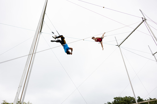 Two trapeze artist flying together in the sky