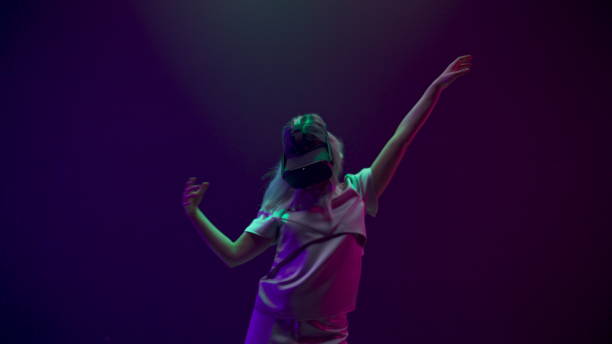 istock Blonde woman dancing in vr glasses at neon light. 1456931284