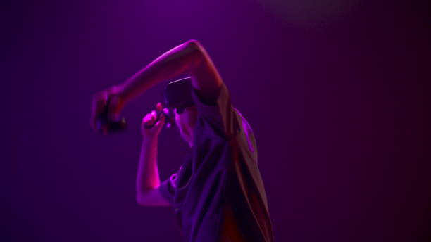 istock Closeup man playing virtual game using invisible sword. Neon colours room 1456932379
