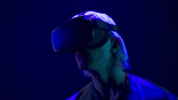 istock Focused VR headset man watching 3d movie neon light closeup. Future technologies 1456934630
