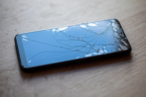 Smartphone with broken touchscreen screen on table desktop stock photo