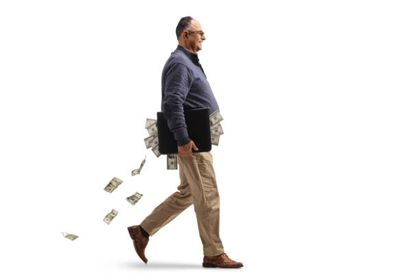 Full length profile shot of a mature man walking with a briefcase full of money stock photo
