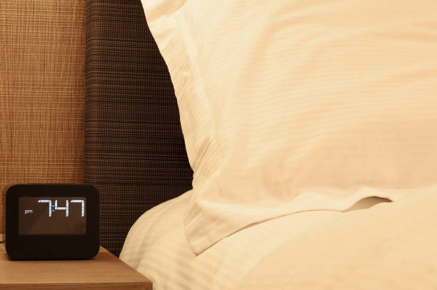 istock White pillow and electronic alarm clock stands on a bedside table in the room. relax concept 1456949453
