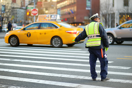 New York - March 21, 2015: NYPD officer regulating traffic in Chinatown district of New York City, one of oldest Chinatowns outside Asia.