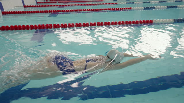 Girl teenager swimmer starts from the wall of the pool and swims butterfly