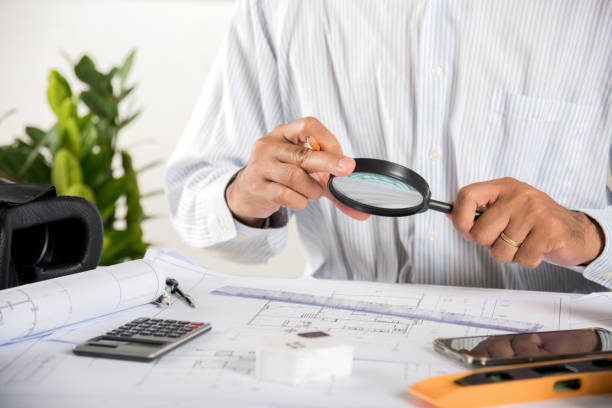 istock Architectural interior designer working holding magnifying glass and look on blueprint 1456957717
