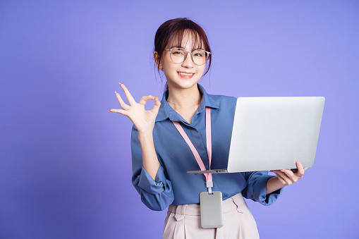 Photo of young Asian businesswoman holding laptop on background