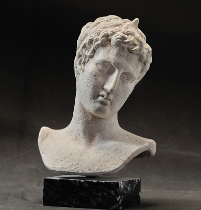 An ancient statue of a young man from ancient Greece presumed to be a  philosopher or poet, severe and sad. Small reproduction of original
