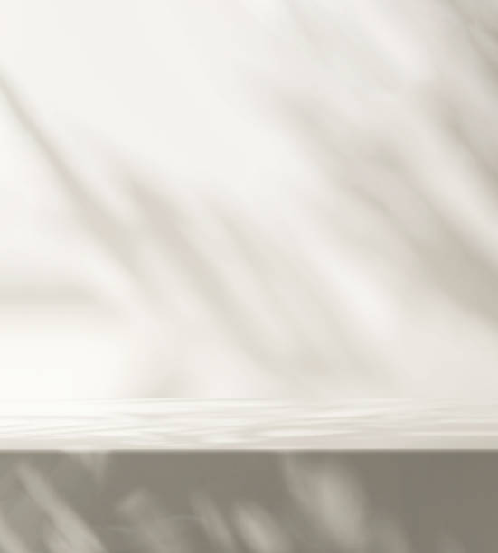 istock Modern, minimal empty white marble counter table top, in dappled sunlight, leaf shadow on white wall 1456962553