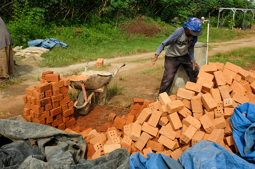 Bandar Lampung, Lampung, Indonesia - January 10, 2023: This photo was taken in a real estate residential building in the city of Bandar Lampung, Lampung province, Indonesia on the morning of January 10 2023. You can see a worker selecting bricks to be used for the walls of the house. Selection of bricks according to the composition will make the building strong and durable