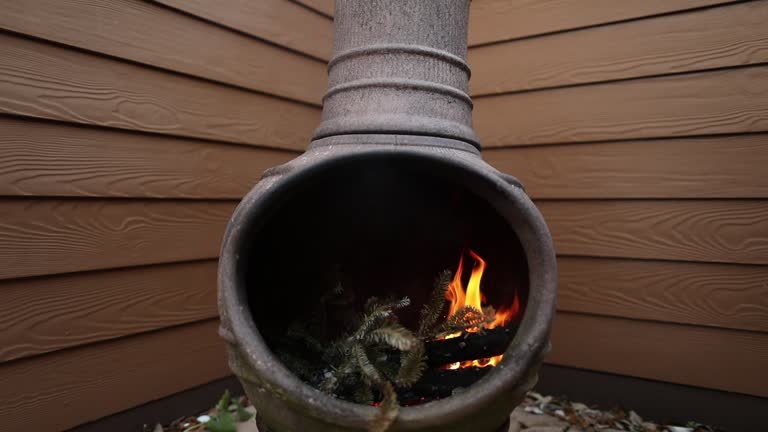 Rustic Chiminea Fire Pit Flaming with Cut Christmas Tree Pine Wood & Needles on a Cold Winter Day is Florida