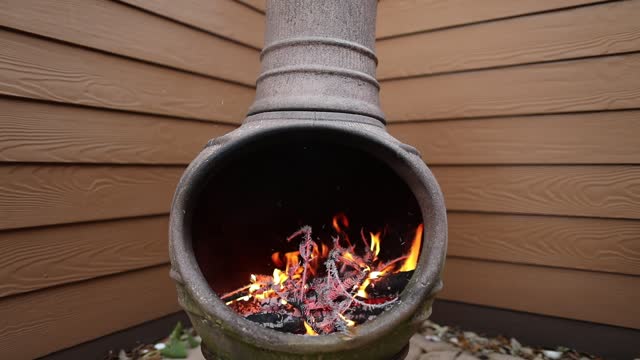 Rustic Chiminea Fire Pit Flaming with Cut Christmas Tree Pine Wood & Needles on a Cold Winter Day is Florida