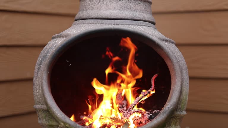 Rustic Chiminea Fire Pit Flaming with Cut Christmas Tree Pine Wood & Needles on a Cold Winter Day is Florida