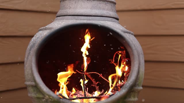 Rustic Chiminea Fire Pit Flaming with Cut Christmas Tree Pine Wood & Needles on a Cold Winter Day is Florida