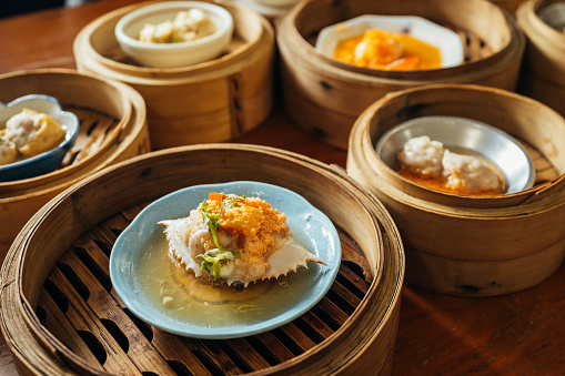 Crab she dim sum stuffed with prawn and topped with egg yolk served in bamboo containers traditional cuisine