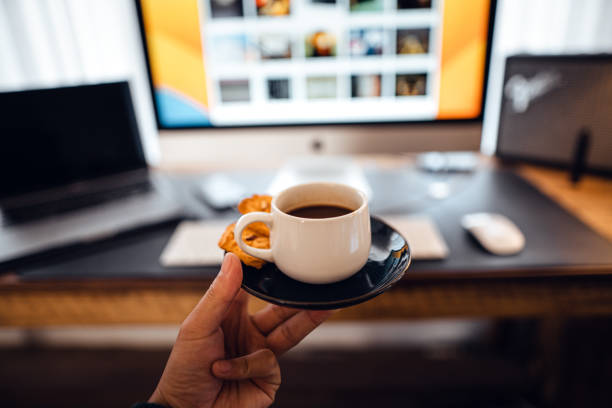 hand holding a cup of coffee at the desk