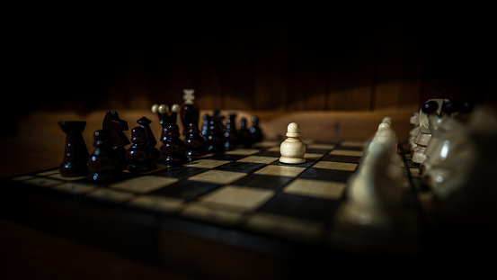 The set of wooden chess pieces element, king, queen rook, bishop, knight, pawn standing on chess board on dark background. Leadership, teamwork, partnership, business strategy concept.