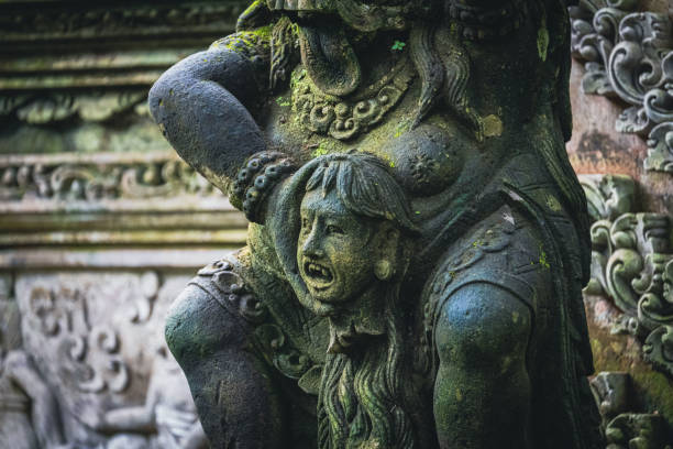 Traditional demon sculpture made of stone in the jungle of the Bali island, Indonesia. Seen at the Monkey Forest in Ubud village.